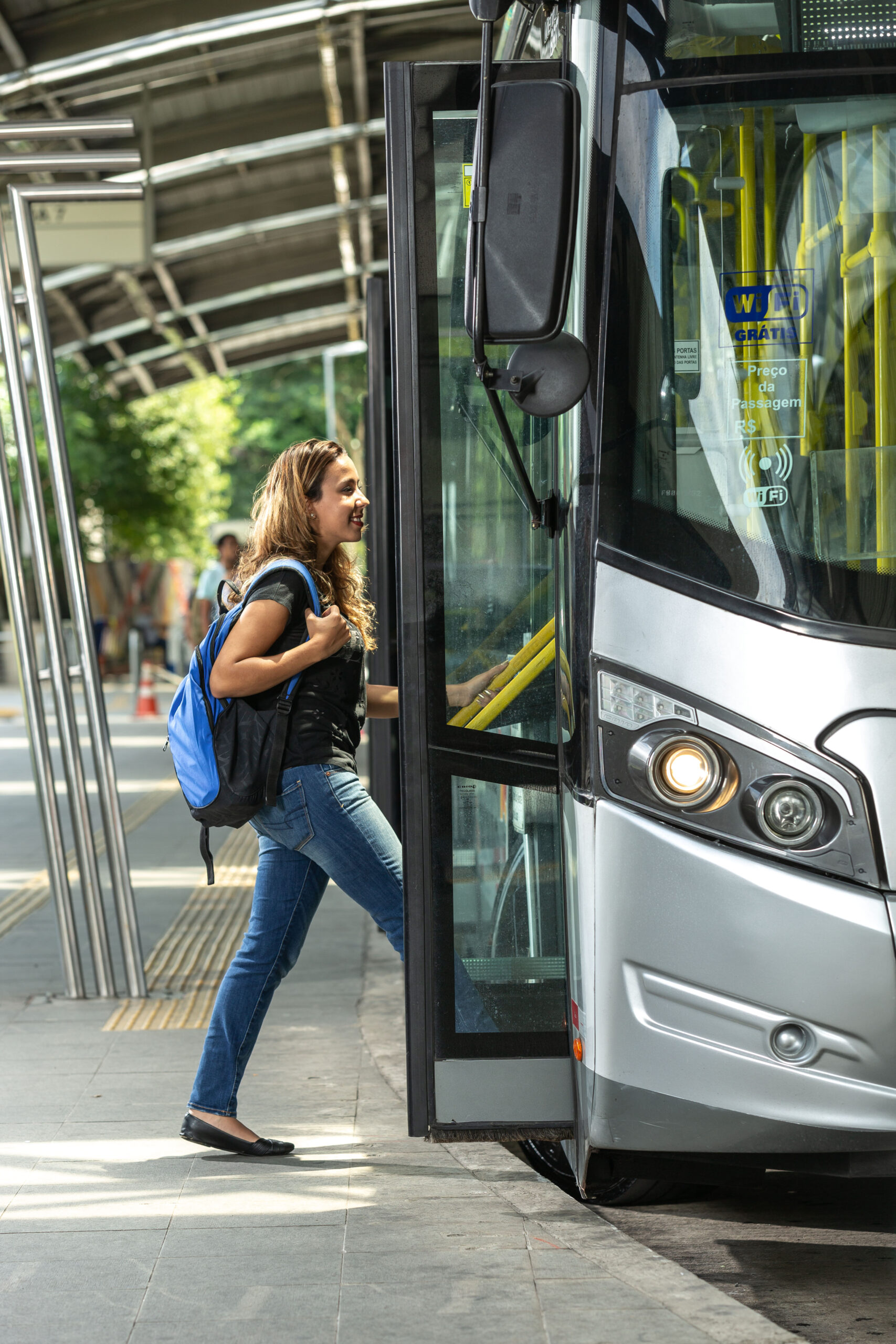 Student or girl getting on a municipal bus, with backpack on their back, in a beautiful and modern terminal